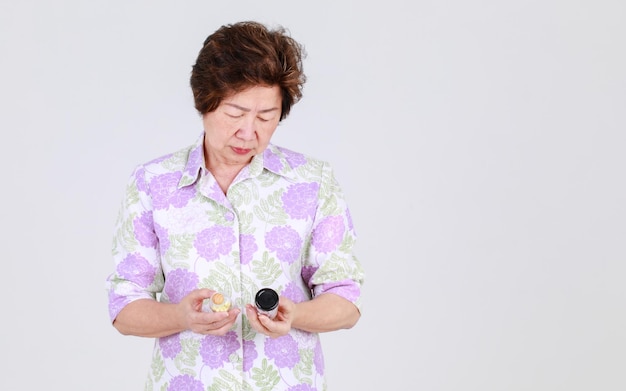 흰색 배경 개념에 대한 바이러스 치료를 위한 항생제 약으로 병원 개업의가 제공한 알약을 들고 있는 나이 든 이모, 노인 아시아 여성