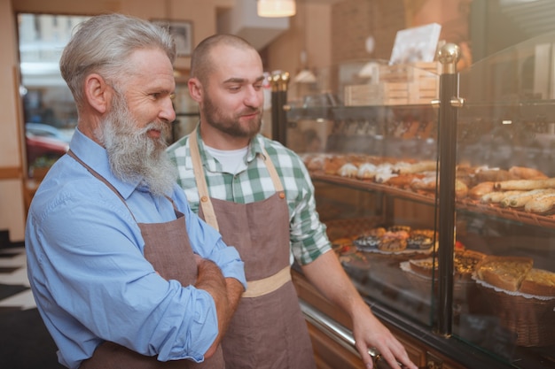 Elderly baker and his son working at their bakery store together