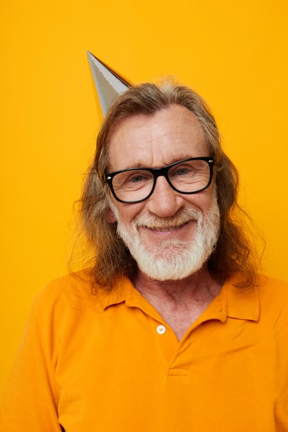 Elderly bearded man wearing glasses with a cap on his head yellow background