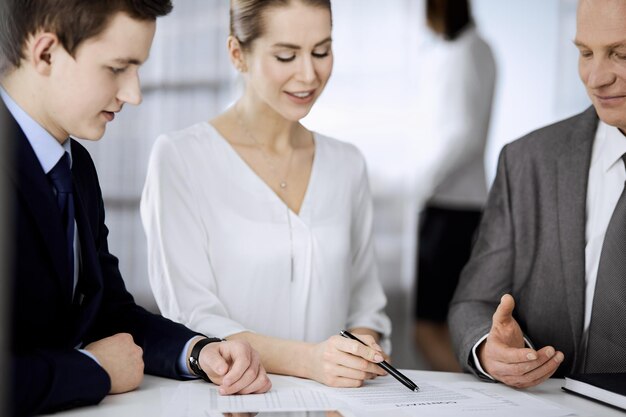 Elderly businessman and group of business people discussing
contract in office. woman and lawyers working together at meeting.
teamwork and cooperation.