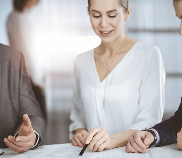 Elderly businessman and group of business people discussing contract in sunny office, close-up.