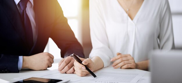 Elderly businessman and group of business people discussing contract in sunny office, close-up.