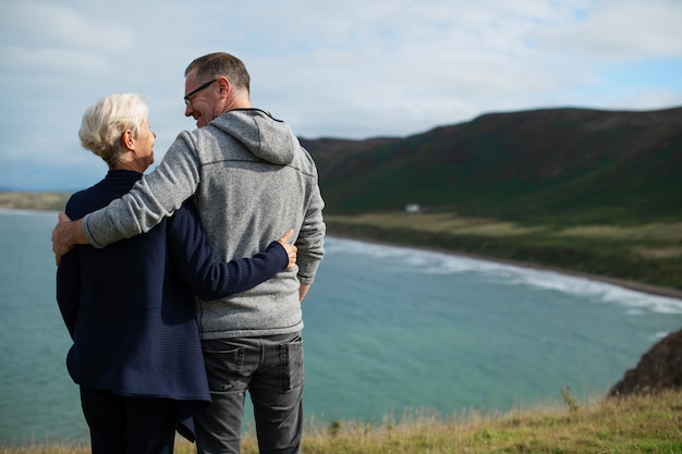 Elderly Caucasian couple man and woman embracing by the coast The elderly couple enjoys the scenic view man and woman sharing a loving moment by the coast Senior couple hugging by the coast