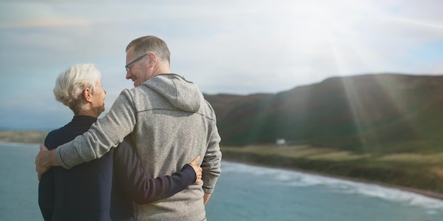 Elderly Caucasian couple man and woman embracing by the sea The elderly couple enjoys the scenic view with the man and woman sharing a loving moment by the sea Senior couple hugging by the sea