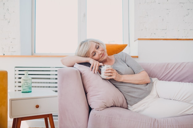 Elderly caucasian old aged woman enjoying afternoon tea at home.