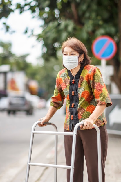 ダウンタウンの大気汚染を保護するためのマスクを身に着けている年配の中国人女性