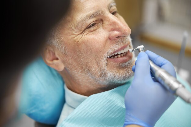 an elderly citizen getting his teeth fixed by a dentist