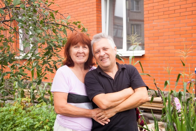 Elderly couple in casual clothes near country house