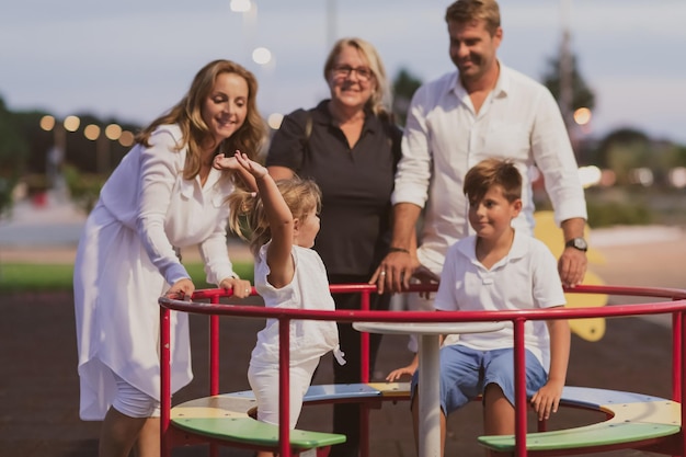 An elderly couple in casual clothes with their children and grandmother spend time together in the p