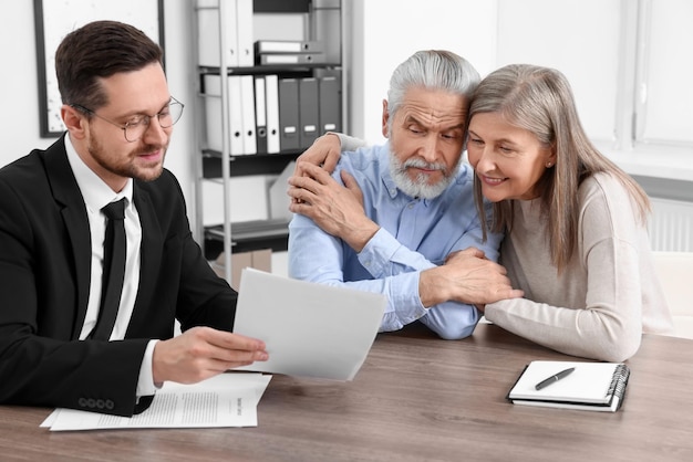 Photo elderly couple consulting insurance agent about pension plan at wooden table indoors