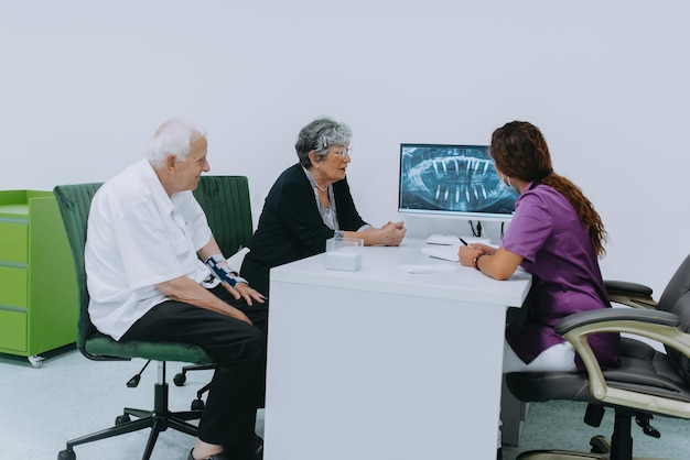 An elderly couple engages in a thoughtful discussion with their dentist about modern denture options