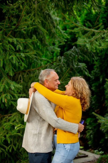 松の木を背景に年配のカップルが抱擁