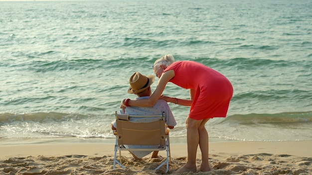 Photo an elderly couple hugs their shoulders at the beach on their summer vacation and they smile and enjoy their vacation