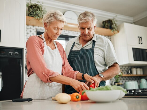 Elderly couple and kitchen for cooking with vegetables for dinner with nutrition food Man woman and in retirement learning to cook for healthy diet in home together love and vegan meal in house