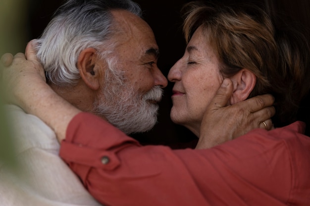 Elderly couple leaning for a kiss in their countryside home