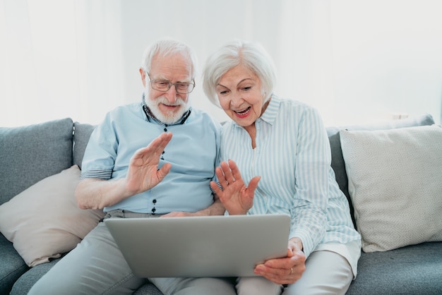 Coppia anziana che fa shopping online su internet con un computer portatile a casa - bella gente anziana felice che utilizza app per pc e social network