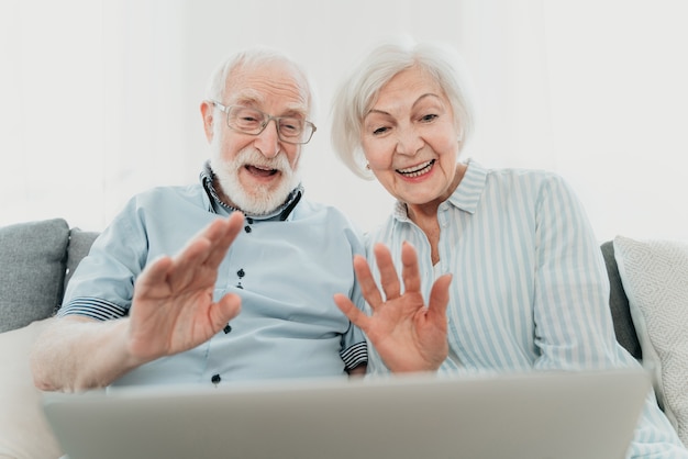 Elderly couple shopping online on internet with computer laptop at home - Beautiful happy senior people using pc and social network apps