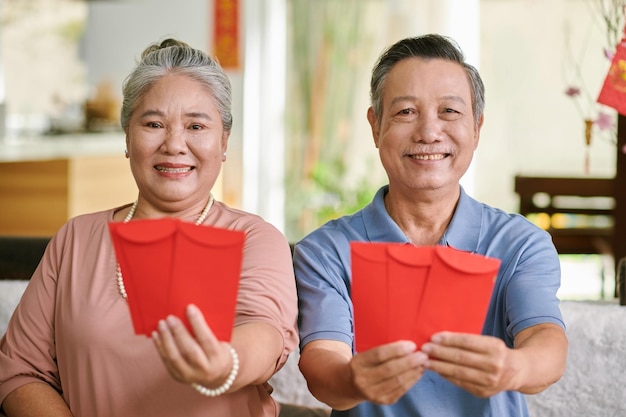 Photo elderly couple showing red evelope