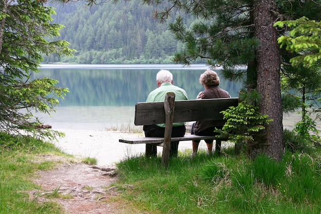 Photo elderly couple sitting on a bench by the lake