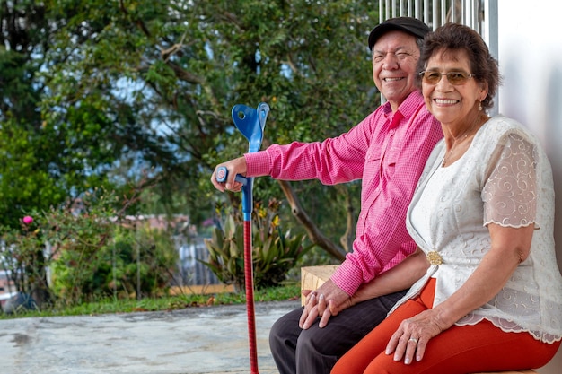Elderly couple smiling at the camera Elderly people sitting on a wooden bench in their backyard