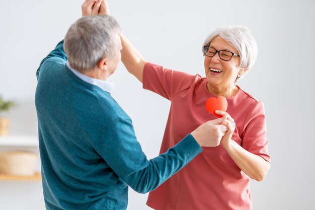 Elderly couple on valentines day Joyful nice senior woman dancing with her husband