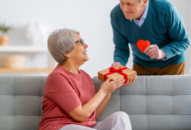 Elderly couple on valentines day Joyful nice senior woman smiling while receiving a gift