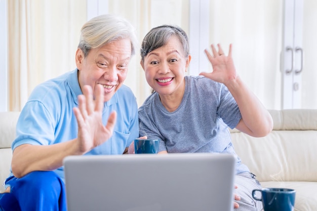 Elderly couple waving hands while doing a video call