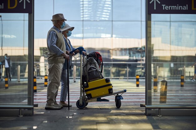 Elderly couple with luggage looking into the distance