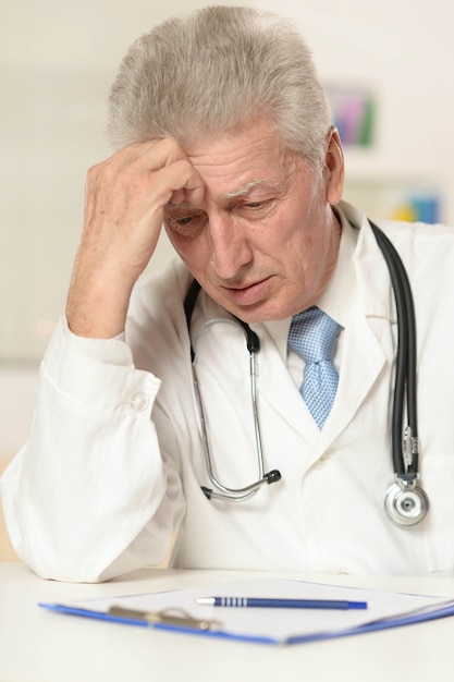 Elderly doctor at a table on a white background