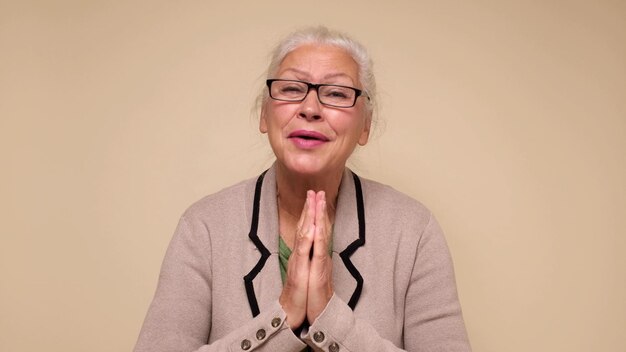 Photo an elderly european woman is praying for help holding her palms together do me a favor