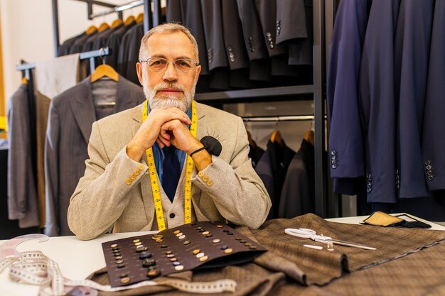 Uomo anziano di bell'aspetto in abito elegante e ricco proprietario di uno studio atelier impegnato con il lavoro