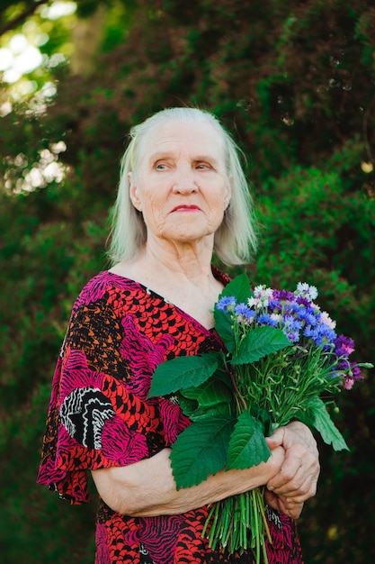 Elderly grandmother with a bouquet of flowers in the park.