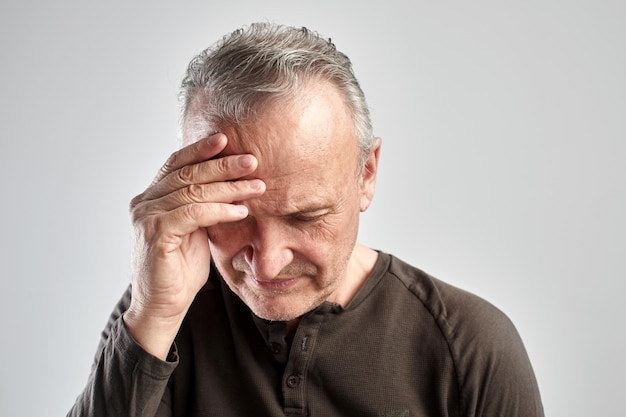 Elderly gray-haired man with expression of pain on face put his hand on head, feels dizzy and cluster headache, migraine, high or low blood pressure isolated on white