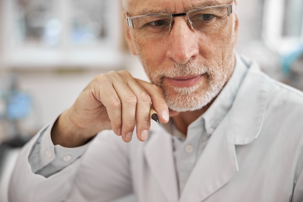 elderly healthcare worker wearing a lab coat and looking thoughtful