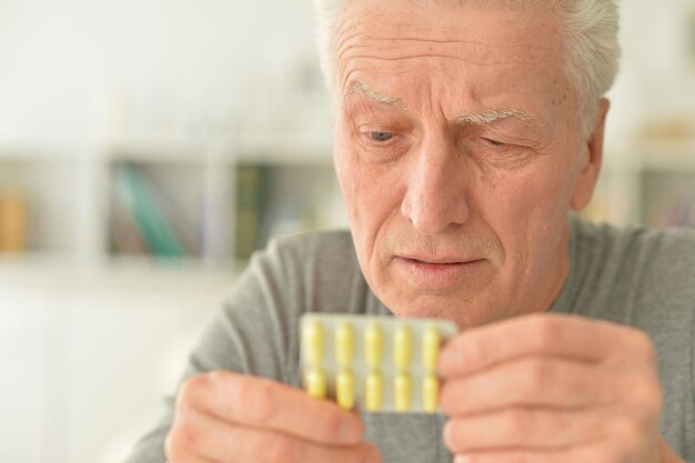 手に錠剤を持つ老人