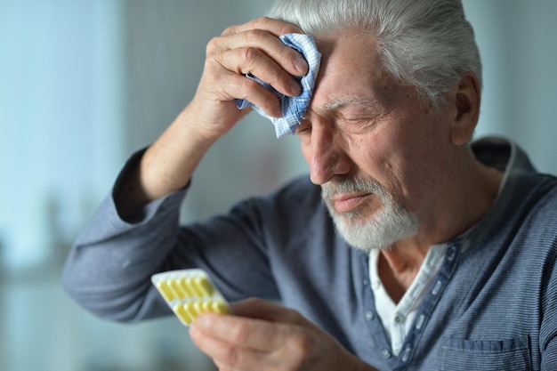 Elderly ill man with pills in hand