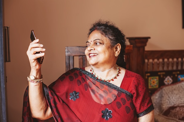 Elderly indian woman using her phone to connect with her family