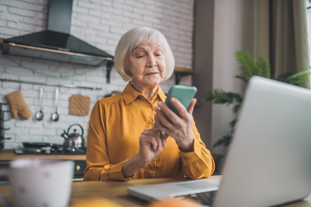 Signora anziana che osserva sullo smartphone