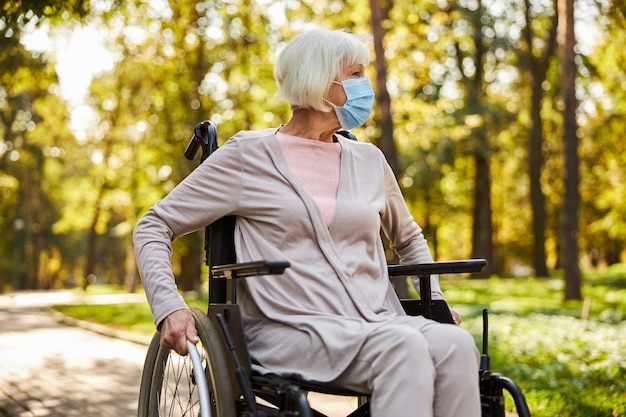 elderly lady pushing her wheelchair on a paved parkway on a sunny autumn day