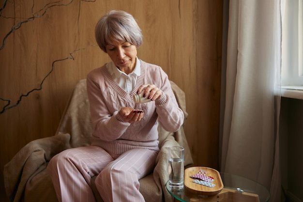 Фото Пожилая женщина принимает таблетки от хронических заболеваний или мультивитамины для здоровья