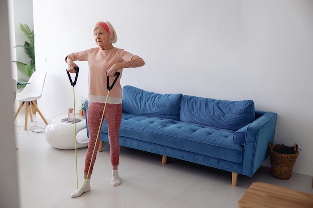 Elderly lady training with exercise band at home