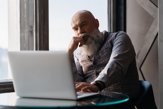 Elderly liquor store owner works on a laptop