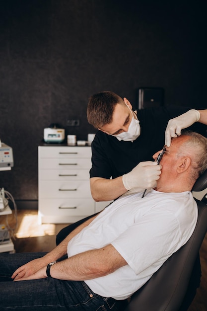 An elderly man at an appointment with a plastic surgeon