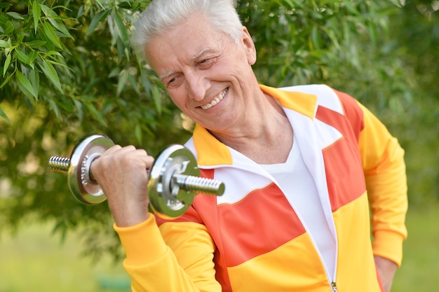 Elderly man exercising with dumbbell in  park