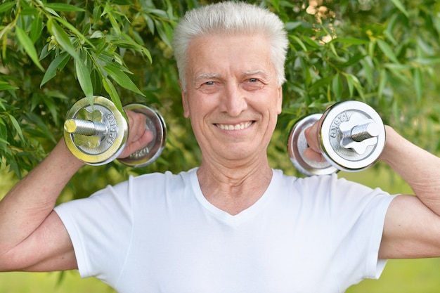 Foto uomo anziano che si esercita con i manubri nel parco