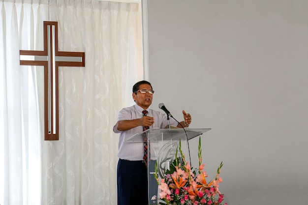 Elderly man gives a speech from a podium in a conference center