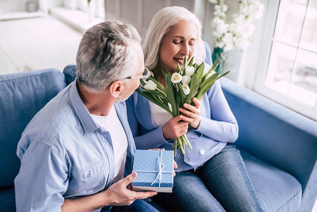 The elderly man giving a gift to a woman with flowers