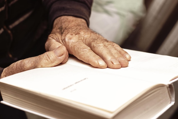 An elderly man a grandfather holds an open book in his hands Leisure for the elderly Reading a book