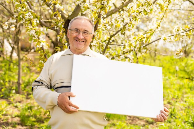 elderly man holding blank photo canvas.