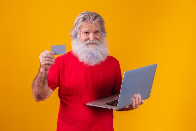 Elderly man holding laptop computer and bank credit card. Online shopping transaction. Mobile banking cashless method.